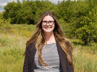 Gillian Ferguson-Martin standing in front of a field and trees, smiling at the camera.